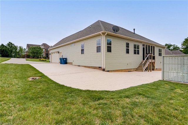 rear view of house featuring concrete driveway, a yard, and a garage