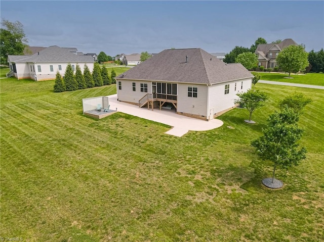 rear view of property with a yard, a shingled roof, and a patio area