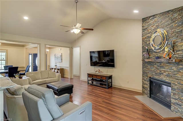 living room with ceiling fan, a stone fireplace, vaulted ceiling, wood finished floors, and recessed lighting