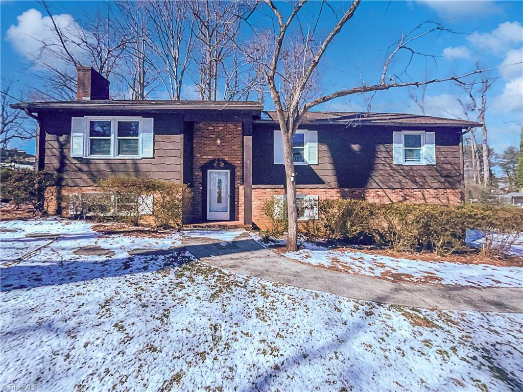 split foyer home featuring brick siding and a chimney