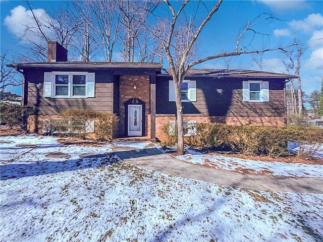 split foyer home featuring brick siding and a chimney