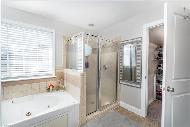 full bath featuring tile patterned flooring, a spacious closet, a stall shower, and a jetted tub