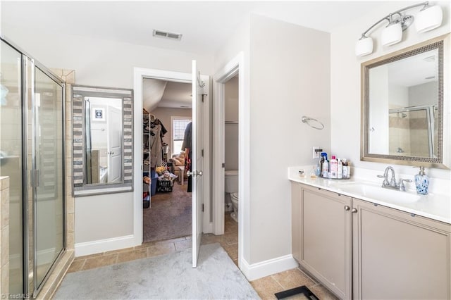 bathroom featuring visible vents, toilet, a stall shower, baseboards, and vanity