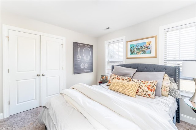 carpeted bedroom with baseboards, visible vents, and a closet