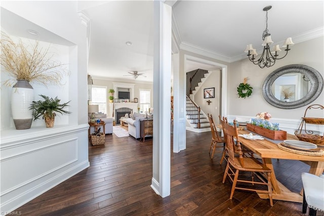 dining room with stairs, a fireplace, dark wood-style flooring, and ornamental molding