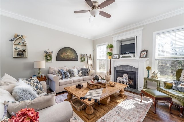 living room with ornamental molding, a tile fireplace, and wood finished floors