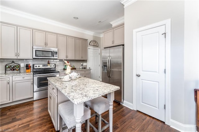 kitchen featuring tasteful backsplash, a kitchen bar, ornamental molding, dark wood-style floors, and stainless steel appliances