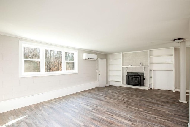 unfurnished living room with wood-type flooring, a brick fireplace, and a wall unit AC