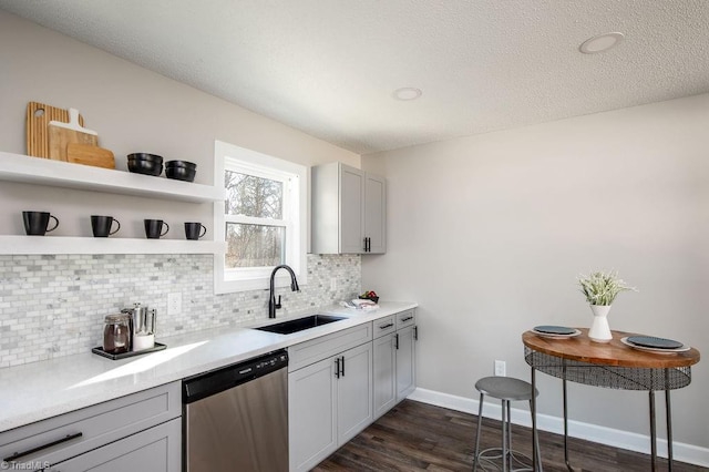 kitchen with dark wood-type flooring, sink, gray cabinetry, dishwasher, and decorative backsplash