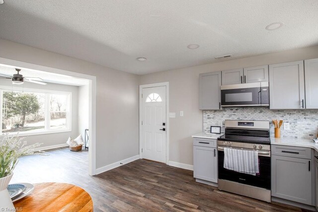 kitchen featuring tasteful backsplash, a textured ceiling, dark hardwood / wood-style floors, gray cabinets, and stainless steel appliances