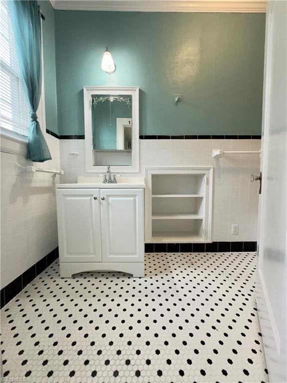 216 Rawley Ave, Mount Airy, NC 27030 - bathroom with tile walls, tile patterned floors, a wainscoted wall, vanity, and ornamental molding