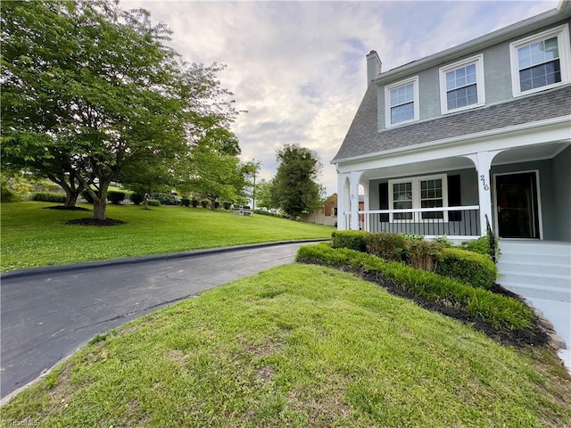 216 Rawley Ave, Mount Airy, NC 27030 - view of property exterior with a porch, stucco siding, a lawn, and a chimney