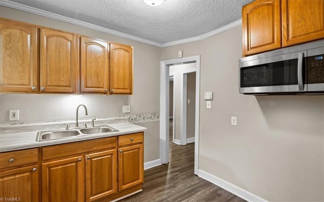kitchen with a textured ceiling, light countertops, a sink, and stainless steel microwave