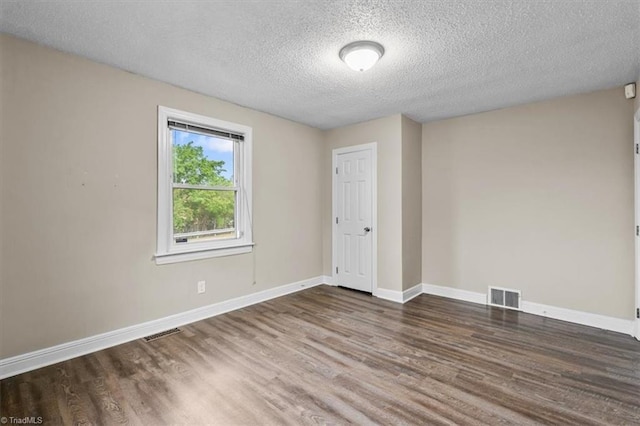 spare room featuring visible vents, wood finished floors, and a textured ceiling