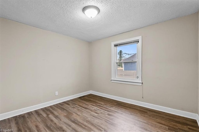 spare room with baseboards, wood finished floors, and a textured ceiling