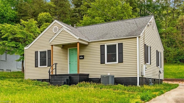 bungalow-style home with cooling unit and roof with shingles