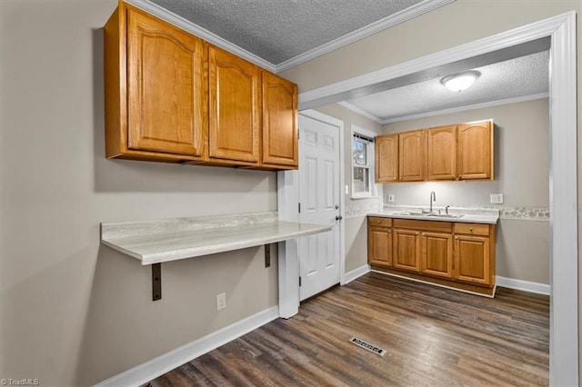 kitchen with a textured ceiling, brown cabinets, light countertops, baseboards, and dark wood-style floors
