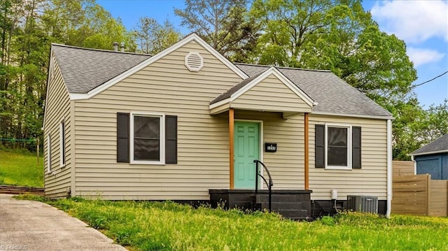 bungalow-style home featuring fence, a shingled roof, and cooling unit