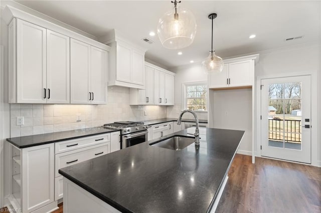 kitchen featuring high end stainless steel range, an island with sink, dark countertops, and a sink