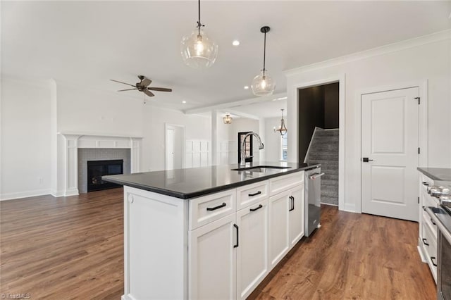 kitchen featuring dark countertops, open floor plan, white cabinetry, and an island with sink