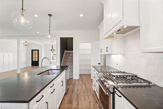 kitchen featuring stainless steel appliances, a sink, white cabinetry, tasteful backsplash, and decorative light fixtures