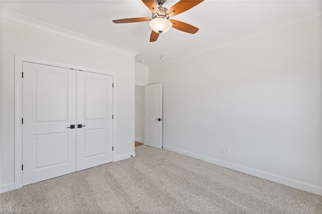 unfurnished bedroom with light carpet, baseboards, ceiling fan, ornamental molding, and a closet