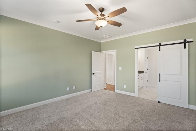 unfurnished bedroom with crown molding, light colored carpet, visible vents, a barn door, and baseboards