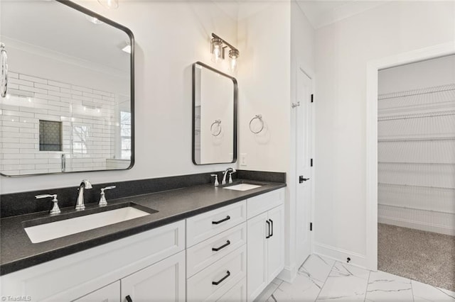 bathroom with marble finish floor, a spacious closet, and a sink