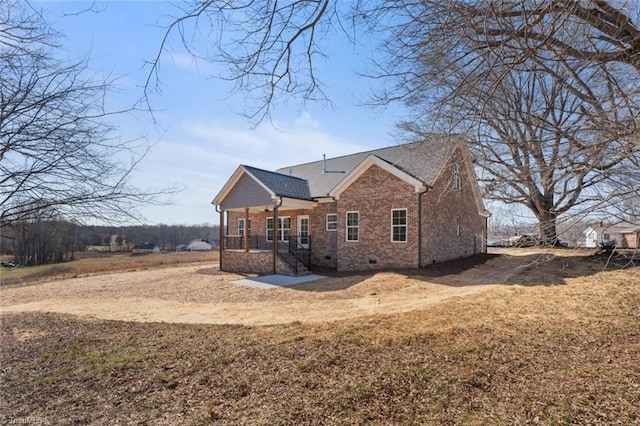 back of property with crawl space, brick siding, a yard, and covered porch