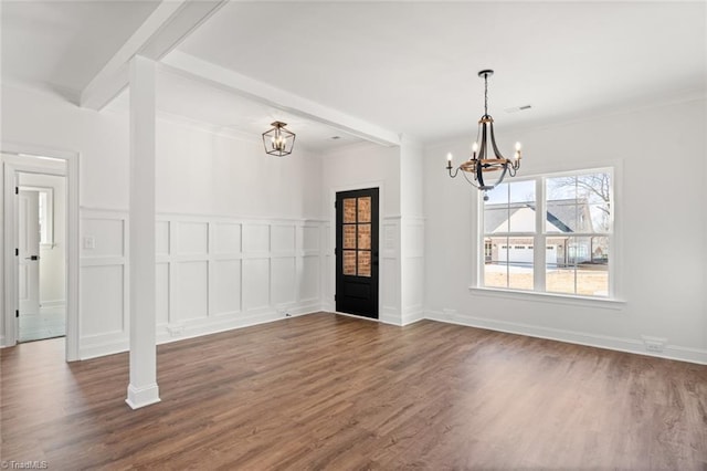 unfurnished dining area with dark wood-type flooring, beam ceiling, a notable chandelier, and a decorative wall