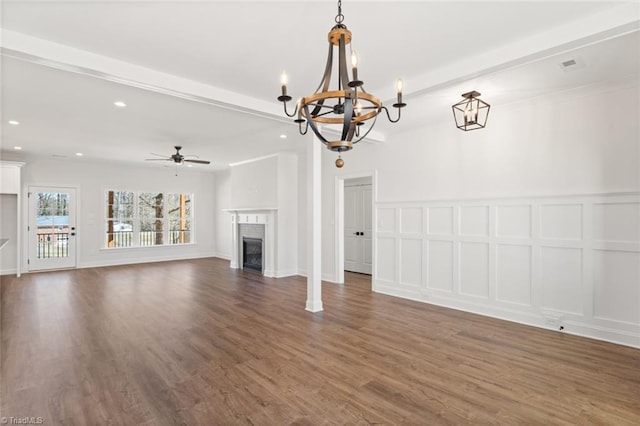 unfurnished living room featuring a glass covered fireplace, dark wood finished floors, beamed ceiling, and a decorative wall