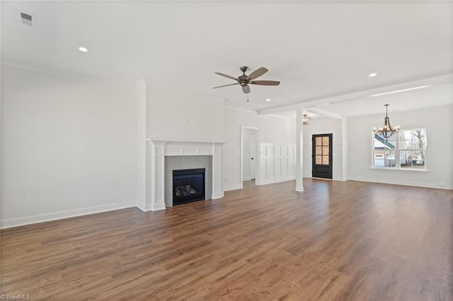 unfurnished living room featuring a tile fireplace, wood finished floors, visible vents, and ceiling fan with notable chandelier