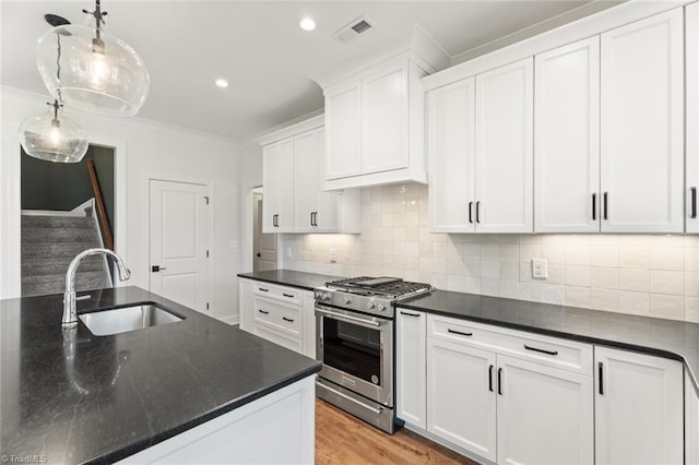 kitchen featuring dark countertops, gas range, and white cabinets