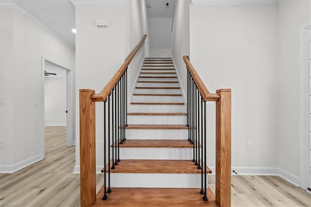 stairway featuring ornamental molding, baseboards, and wood finished floors