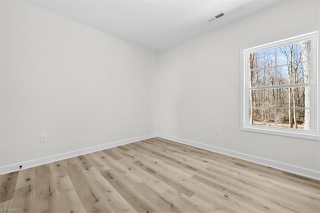 unfurnished room with visible vents, light wood-type flooring, and baseboards