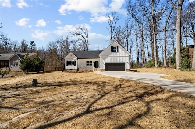 modern inspired farmhouse with concrete driveway, fence, and a garage