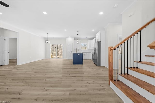 unfurnished living room with stairway, recessed lighting, light wood-type flooring, and ornamental molding