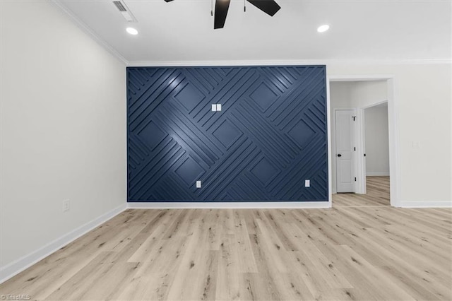 unfurnished room with an accent wall, crown molding, wood finished floors, and baseboards