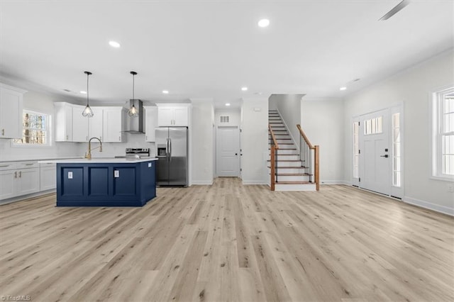 kitchen with white cabinetry, light countertops, wall chimney exhaust hood, and stainless steel appliances