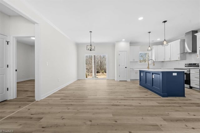 kitchen with stainless steel electric stove, light countertops, blue cabinets, white cabinetry, and wall chimney exhaust hood