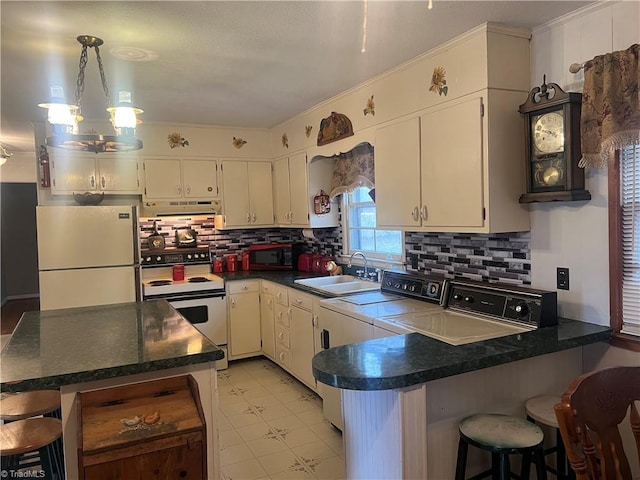 kitchen with refrigerator, kitchen peninsula, white electric range, sink, and a kitchen breakfast bar