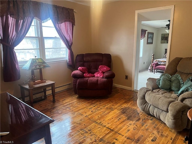 living room featuring ceiling fan, wood-type flooring, and a baseboard heating unit