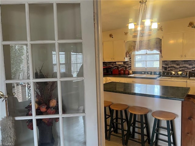 kitchen with pendant lighting, sink, backsplash, a notable chandelier, and a breakfast bar