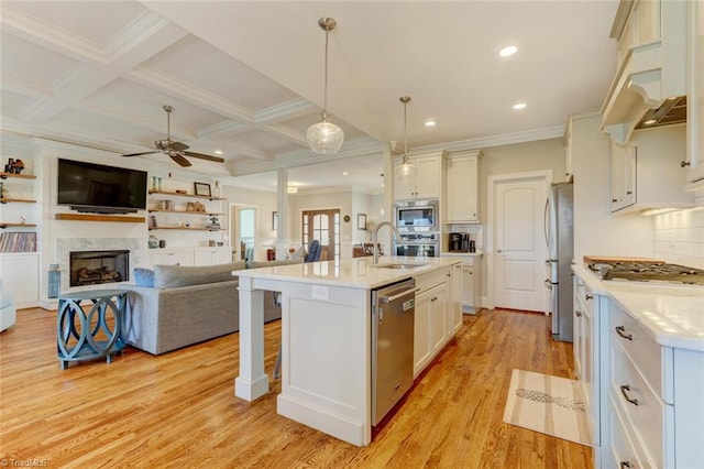 kitchen featuring hanging light fixtures, stainless steel appliances, coffered ceiling, a center island with sink, and light wood-type flooring