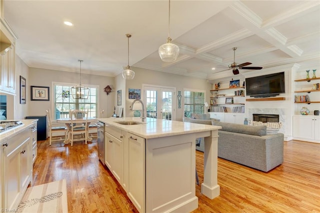 kitchen featuring sink, decorative light fixtures, a kitchen island with sink, and white cabinets