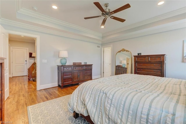 bedroom featuring crown molding, ceiling fan, a tray ceiling, and light hardwood / wood-style flooring