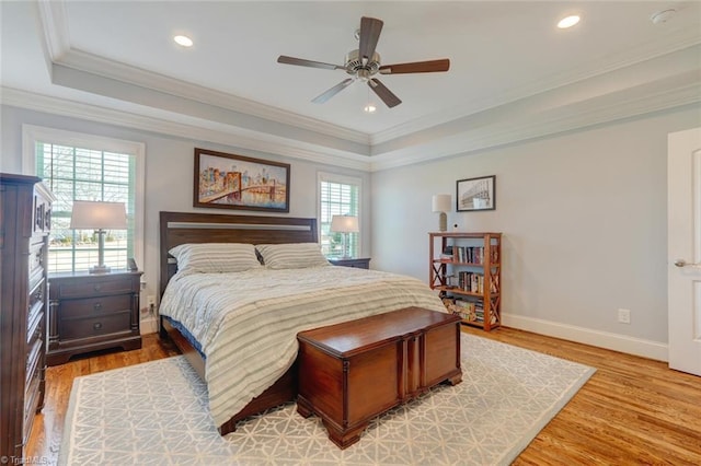 bedroom with a tray ceiling, crown molding, light hardwood / wood-style floors, and ceiling fan