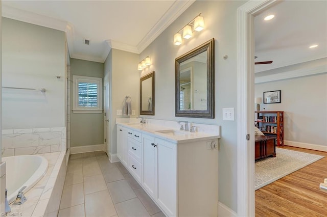 bathroom with crown molding, vanity, a relaxing tiled tub, and wood-type flooring