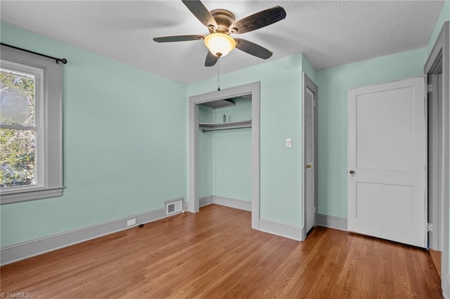 unfurnished bedroom featuring multiple windows, ceiling fan, a textured ceiling, and light hardwood / wood-style flooring