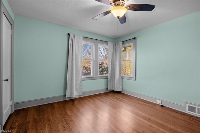 empty room featuring hardwood / wood-style flooring, ceiling fan, and a textured ceiling